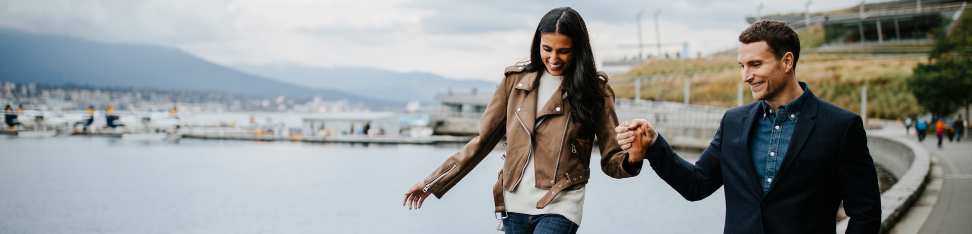 couple hold hands as they walk along boardwalk