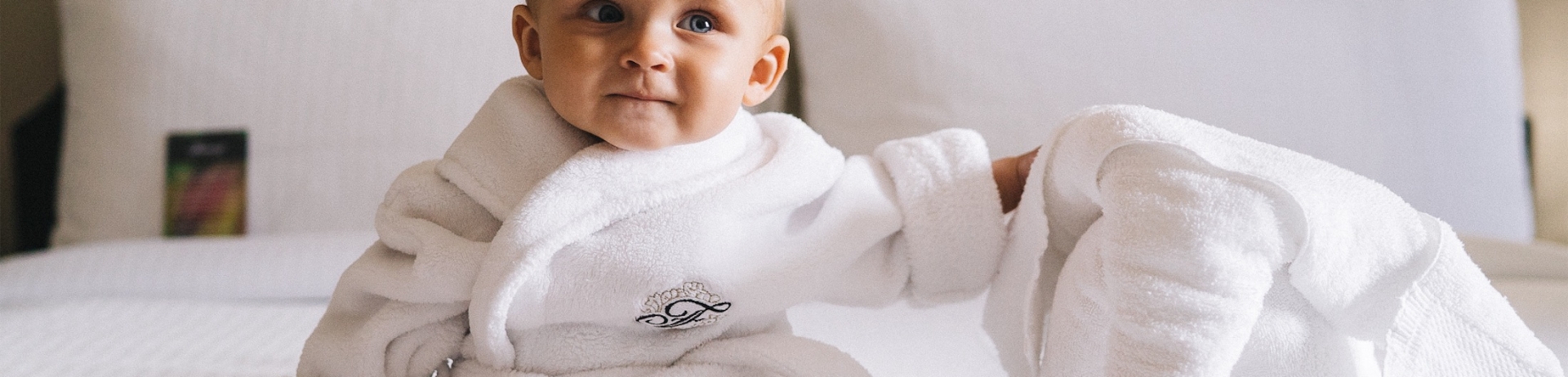 baby in a robe sitting on a bed