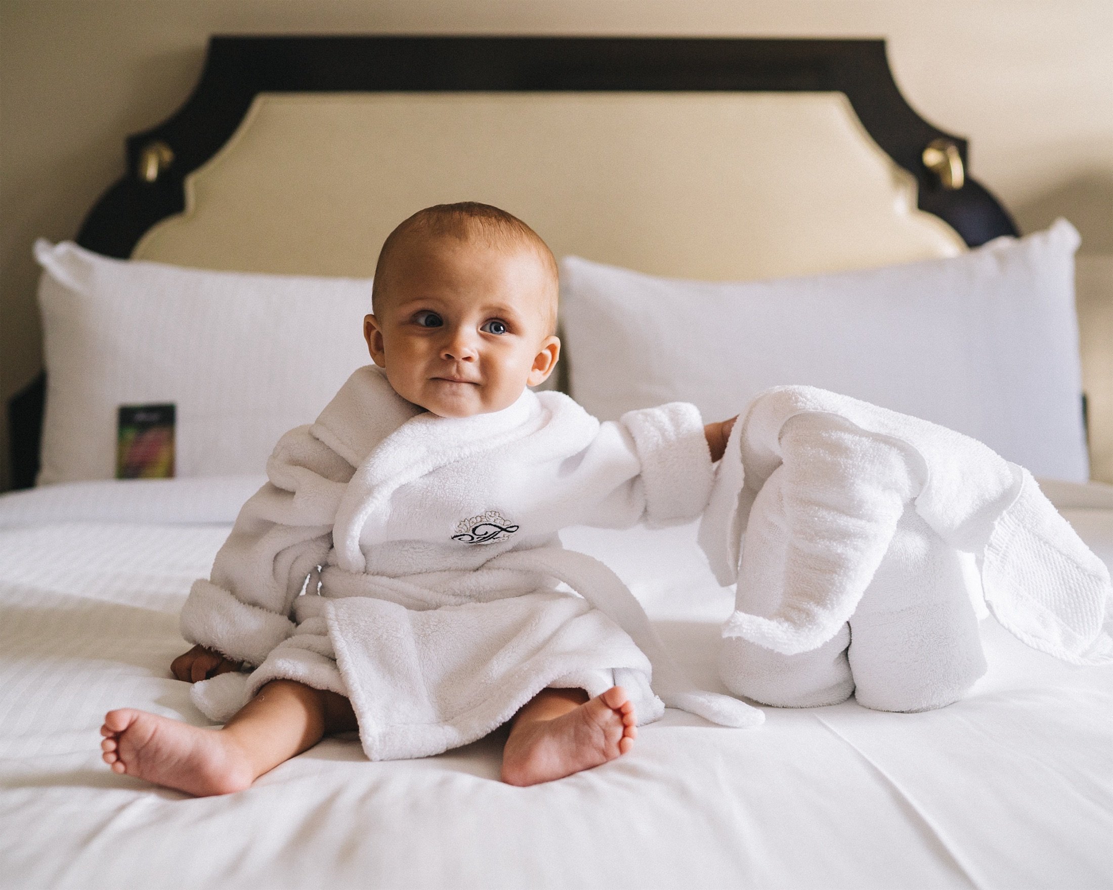 baby in a robe sitting on a bed