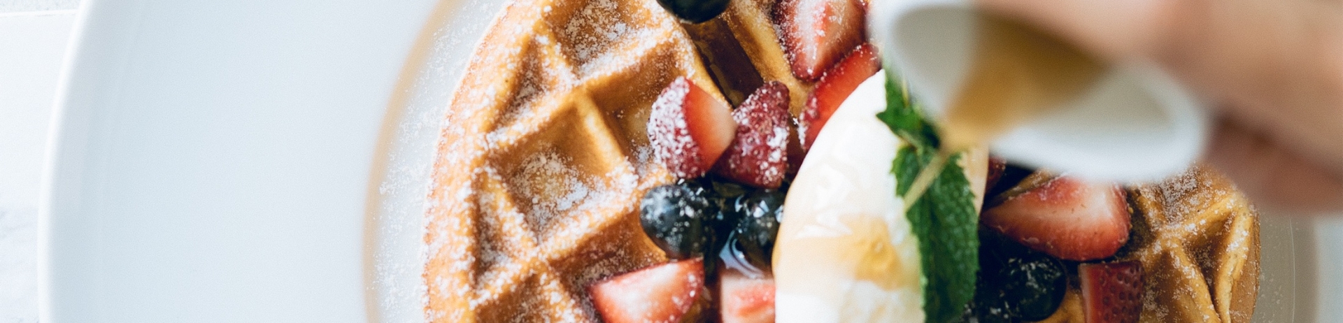 waffle with fresh fruit with syrup being poured on top