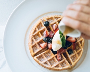 waffle with fresh fruit with syrup being poured on top