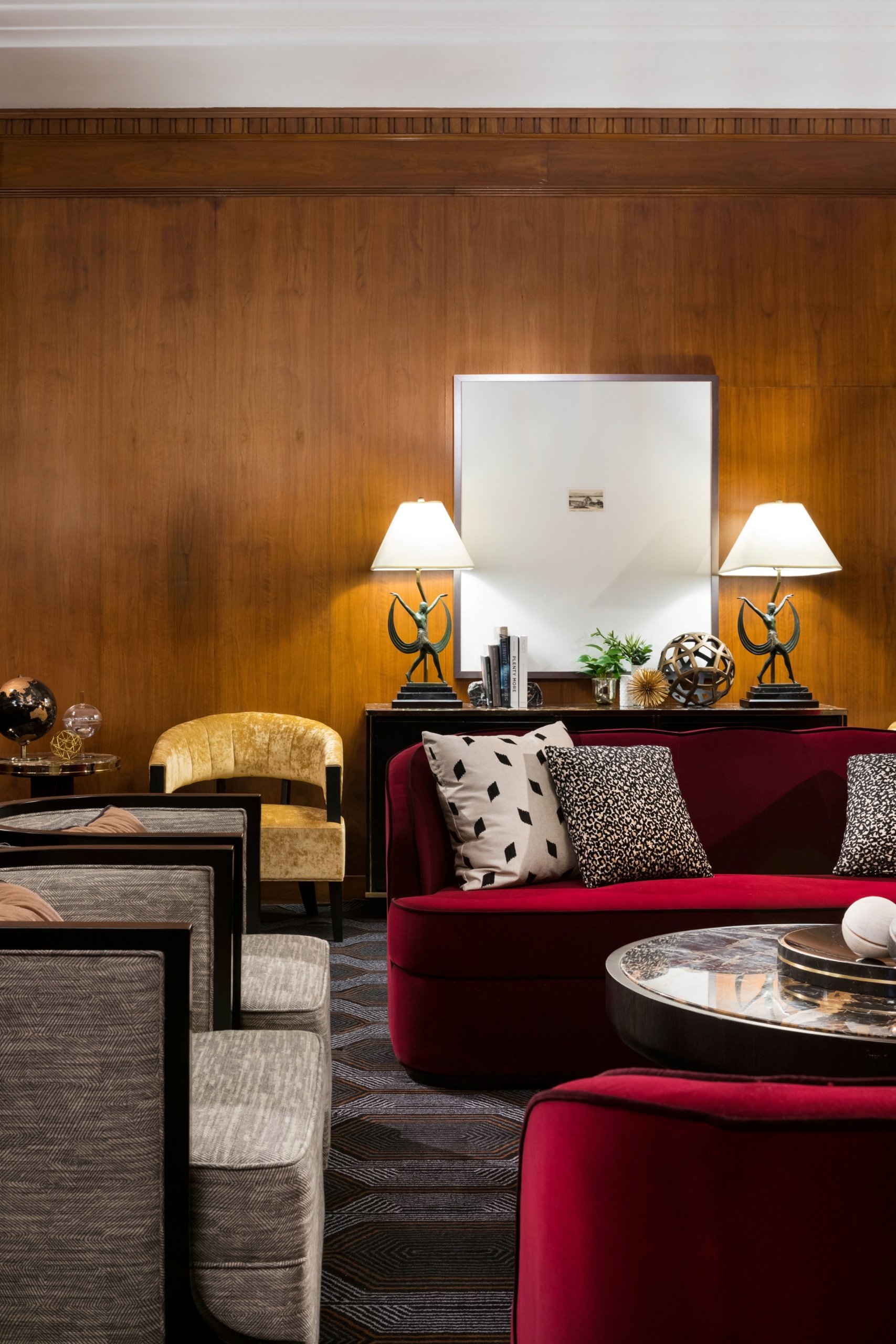 red and grey cushioned sofas in front of a table with decorations and 2 lamps