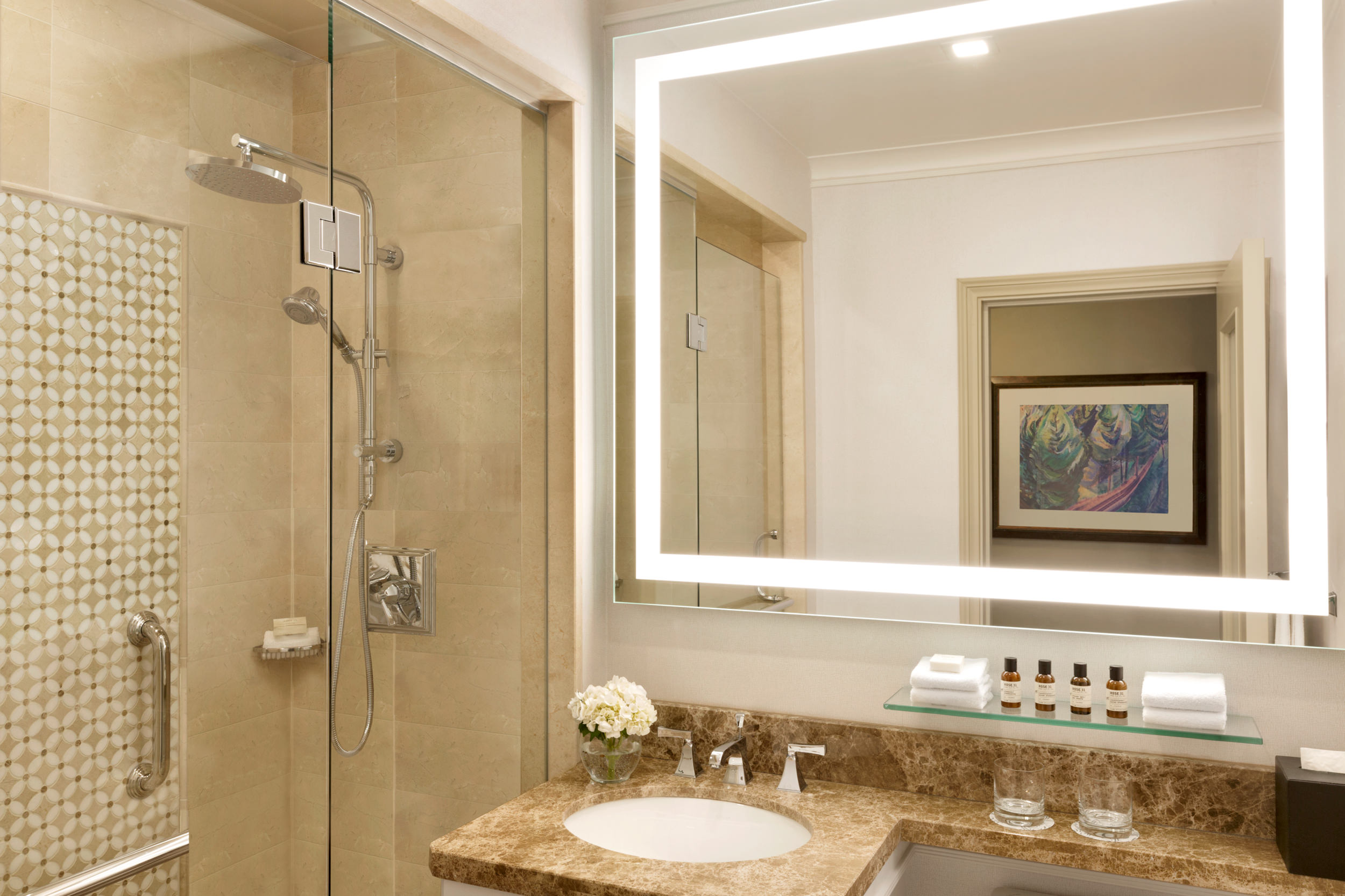A bathroom mirror over a vanity and next to a glass shower