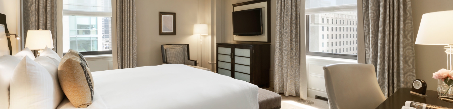 A deluxe corner hotel room with a king bed and city views