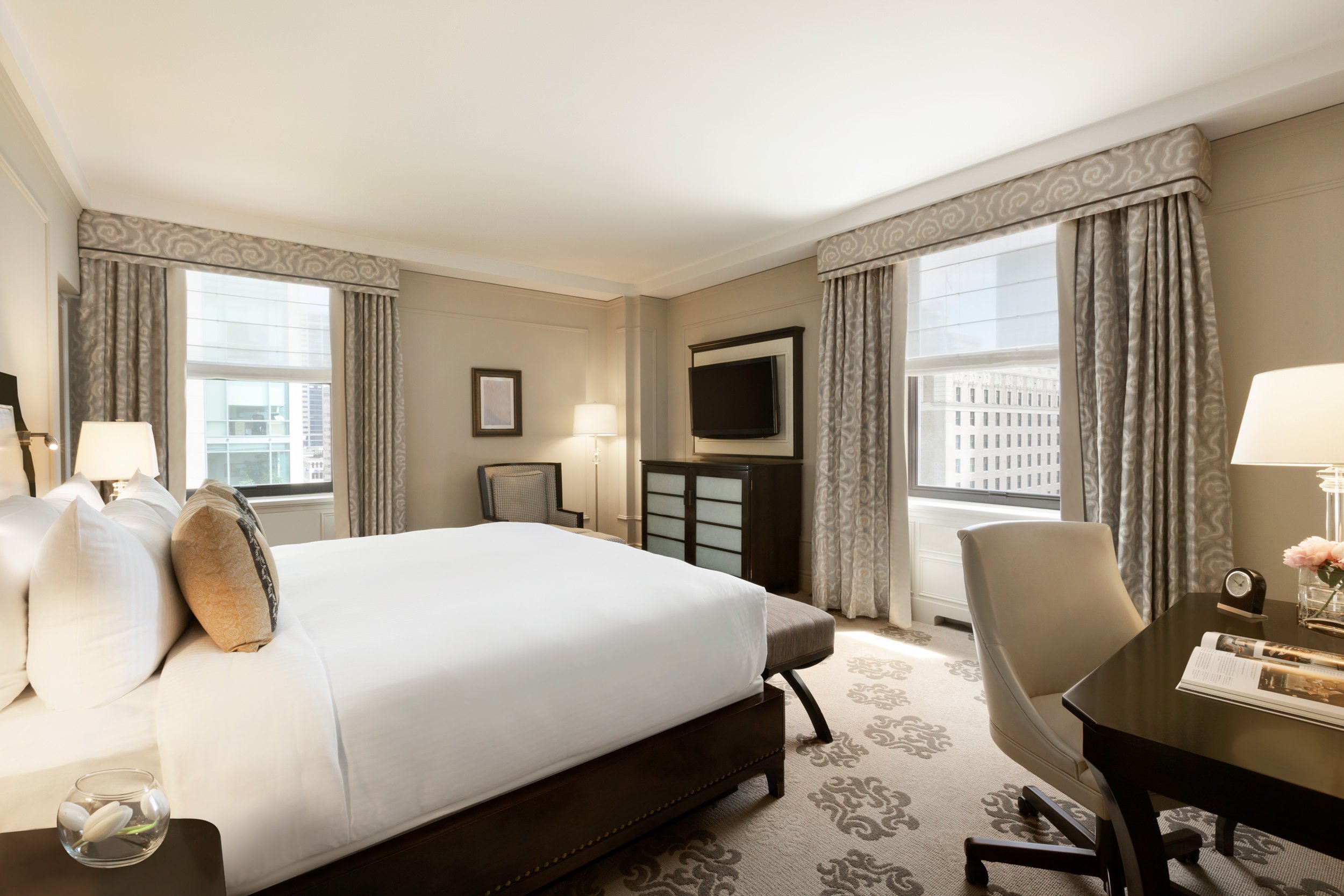 A deluxe corner hotel room with a king bed and city views