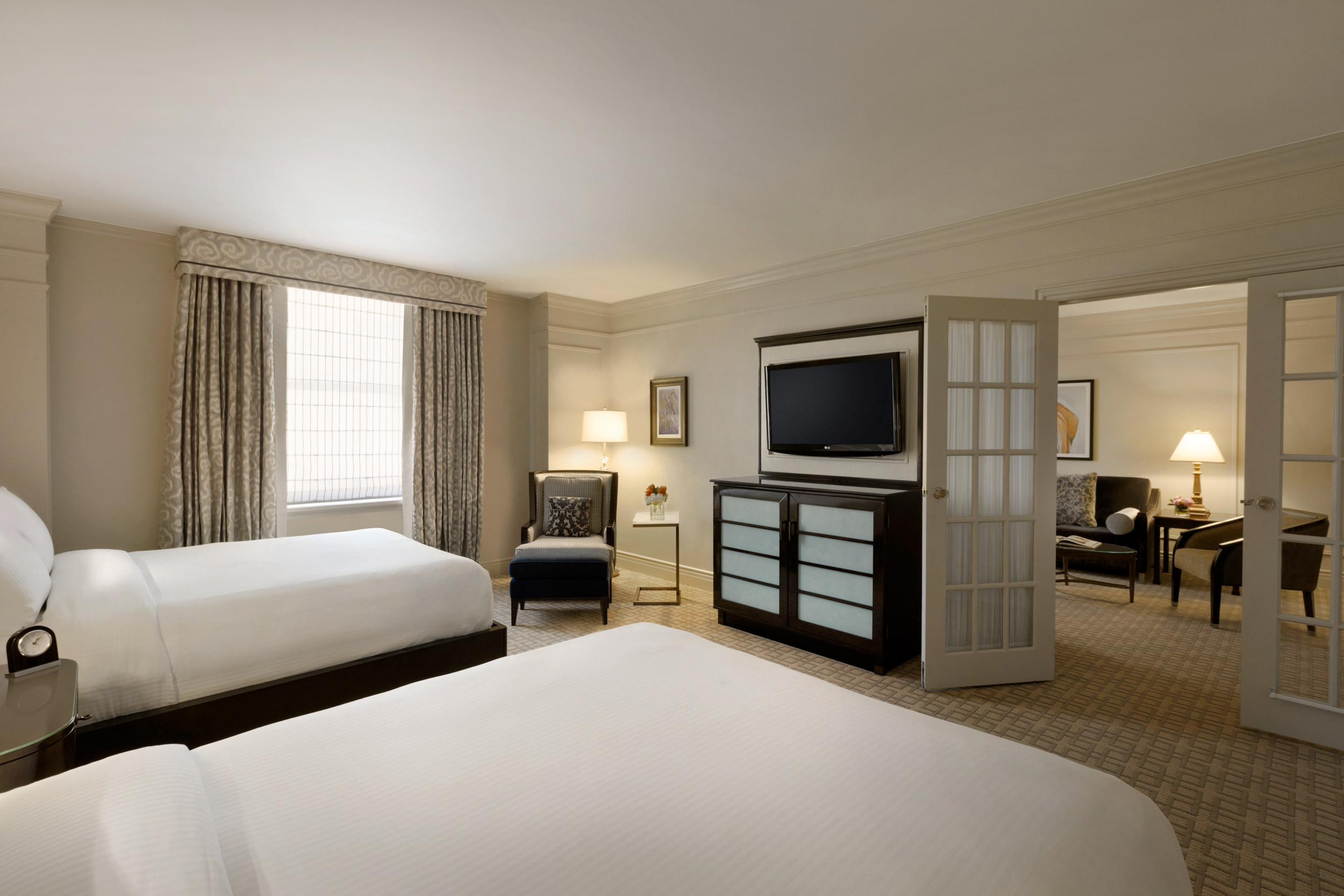 The living room and separate bedroom with two beds in Fairmont Hotel Vancouver's One Bedroom Suite