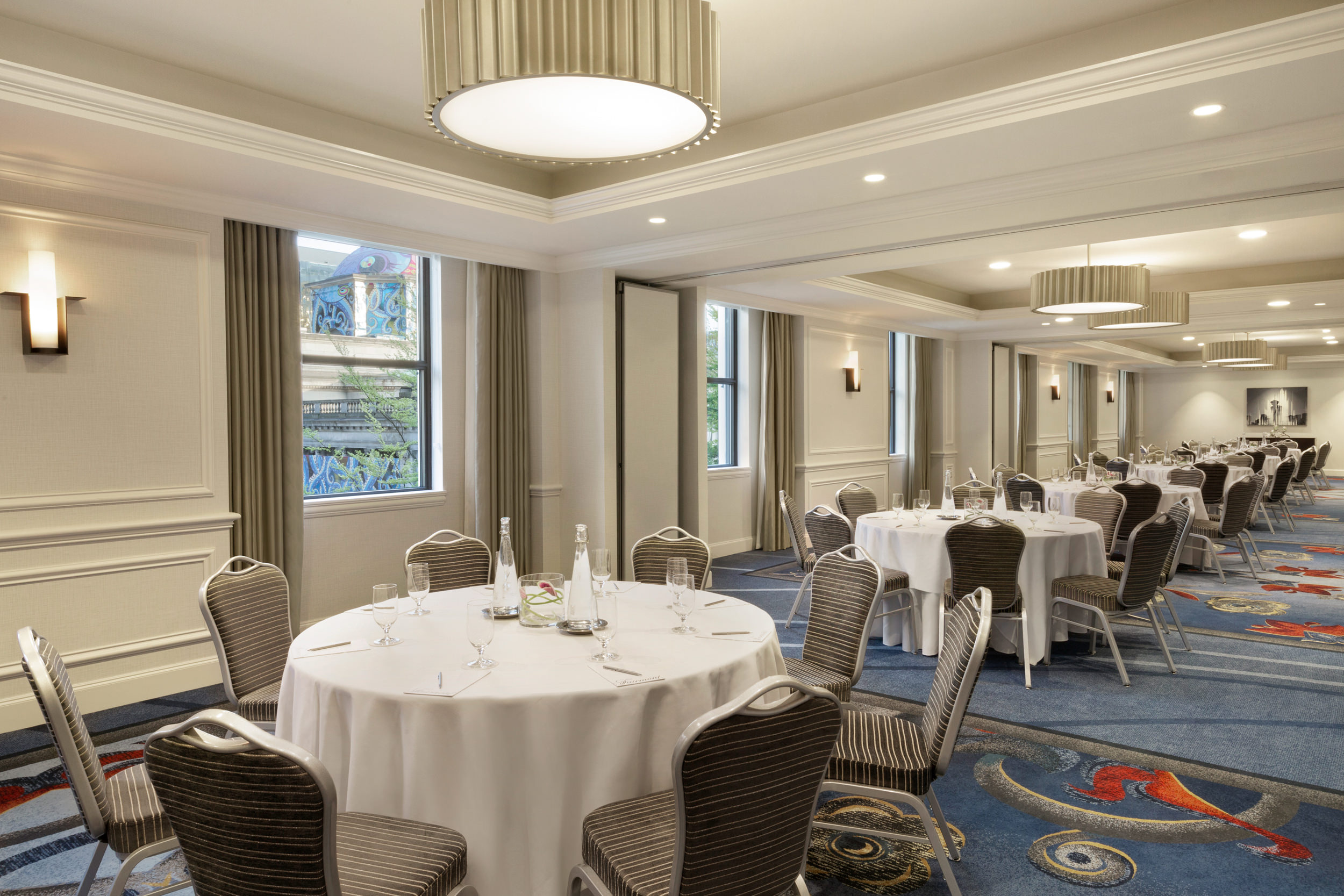 large room with round tables covered with cloths and surrounded by chairs