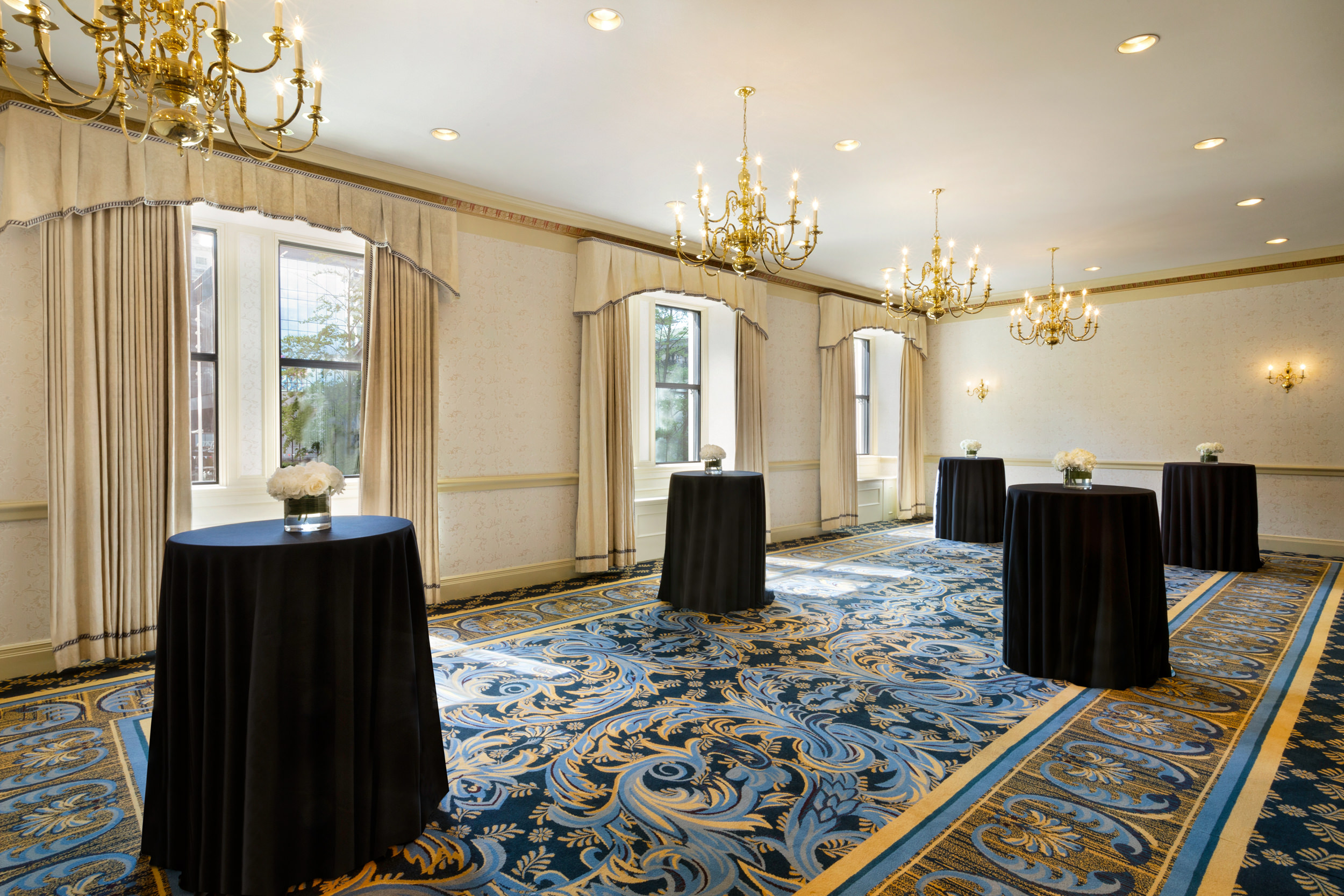 large room with chandeliers, covered tables and a blue floor