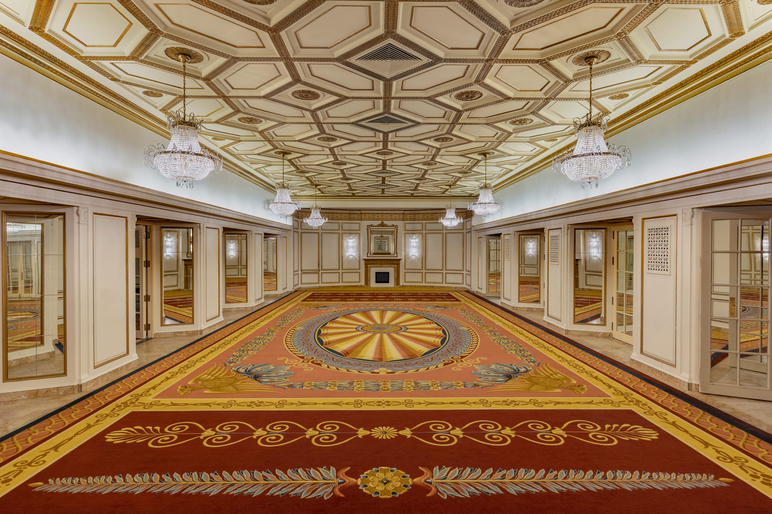 large, empty room with ornate design on the floor and chandeliers hanging from the ceiling