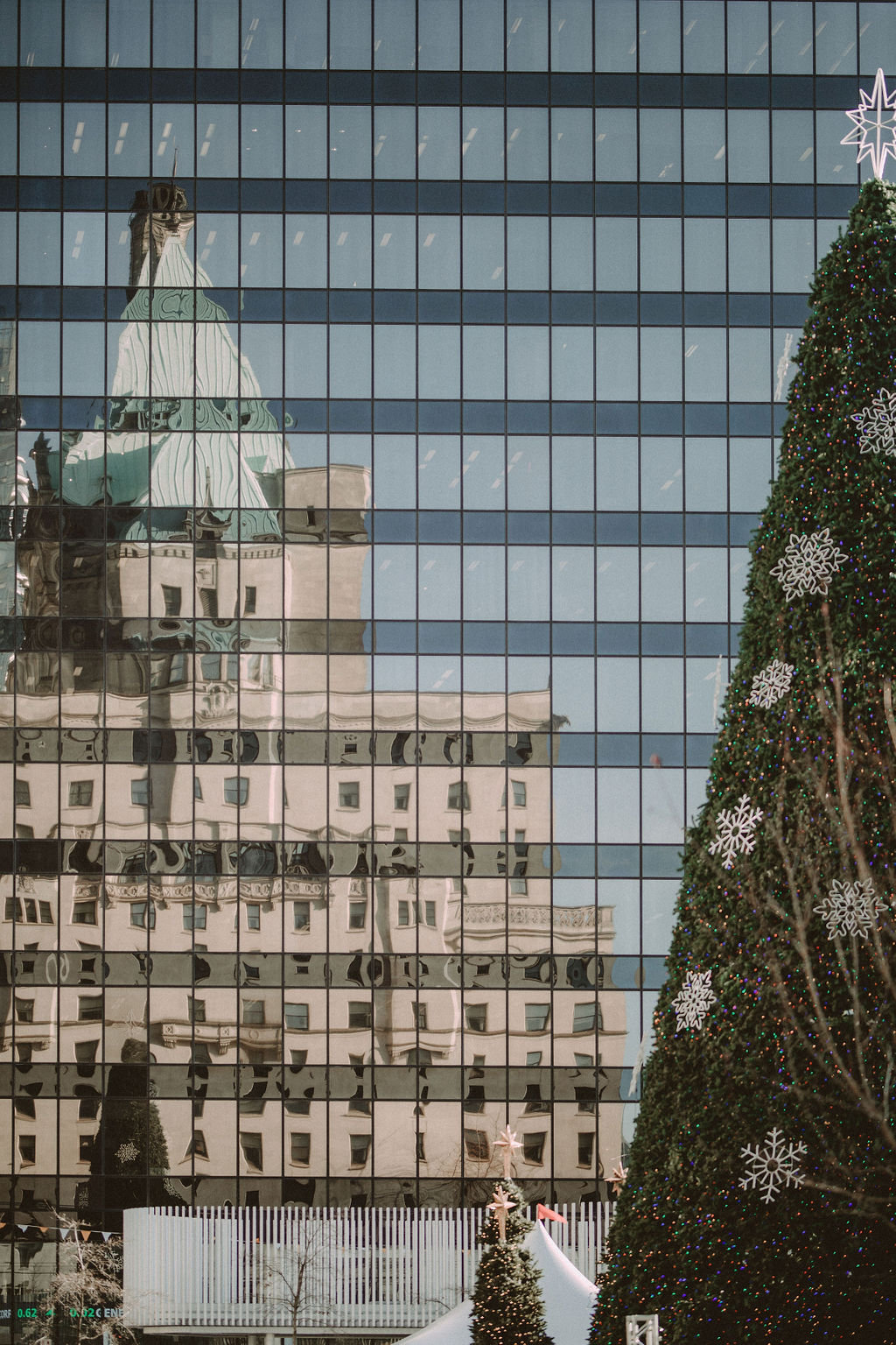 Reflection of Fairmont Hotel Vancouver in building with festive trees