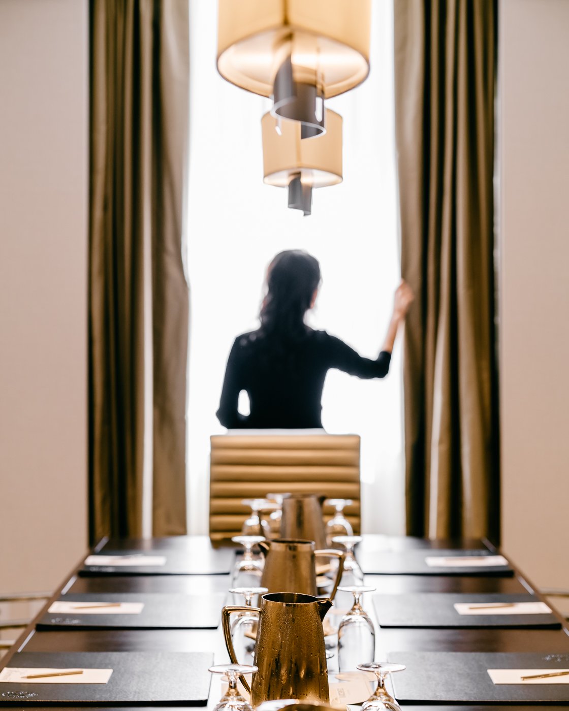 Woman adjusting the curtain in a boardroom at Fairmont Hotel Vancouver