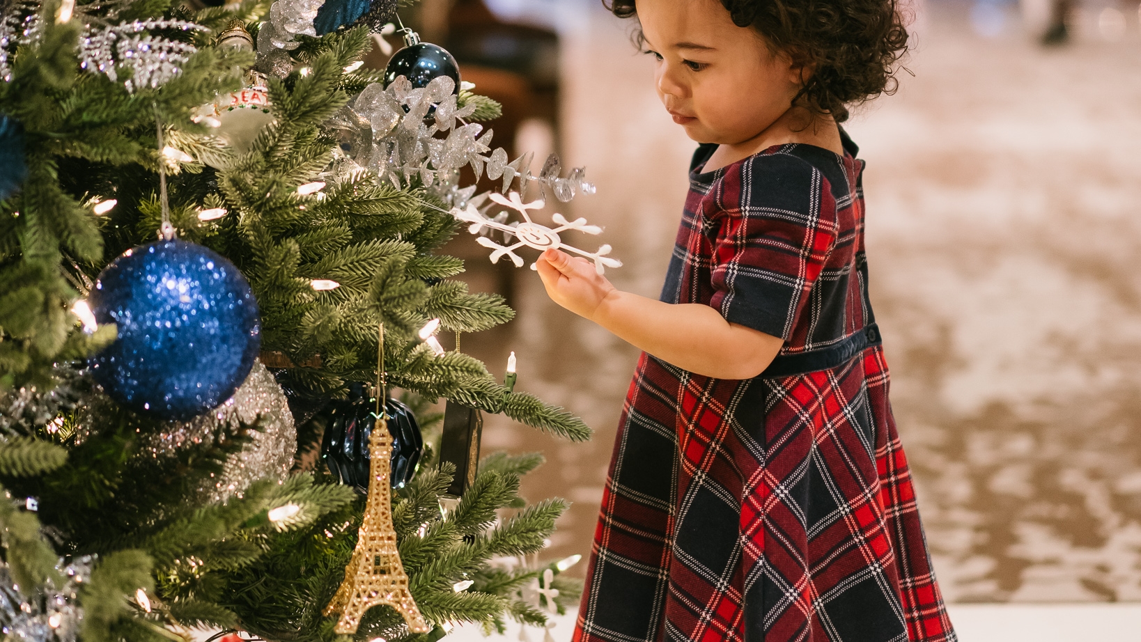 Child in festive outfit in front of Christmas tree at Fairmont Hotel Vancouver