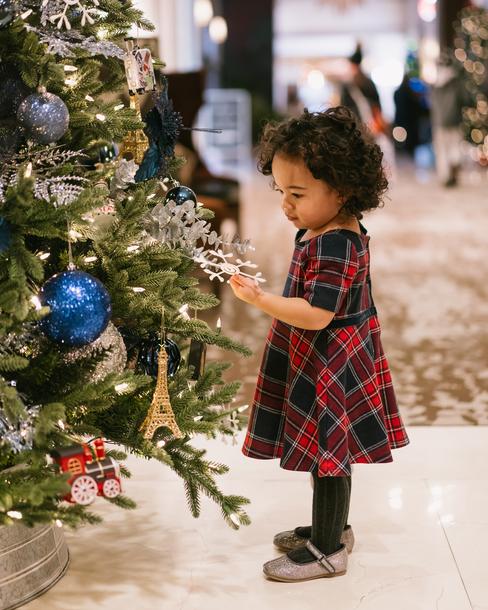 Child in festive outfit in front of Christmas tree at Fairmont Hotel Vancouver