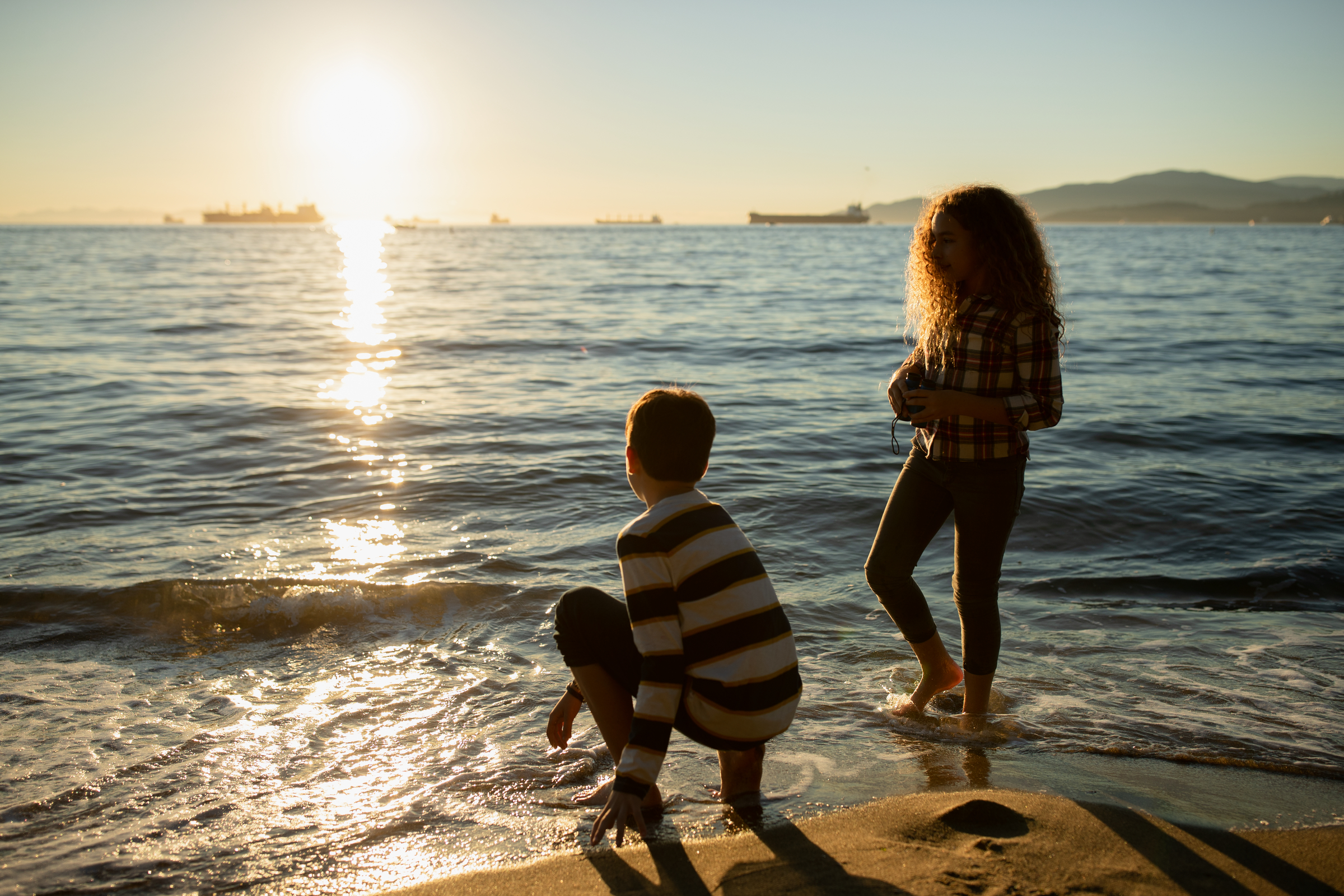 Kids throwing rocks at Third beach at sunset | Credit: Destination Vancouver/Hubert Kang