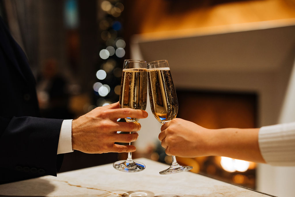 Couple cheers with champagne with fireplace in background at Fairmont Hotel Vancouver